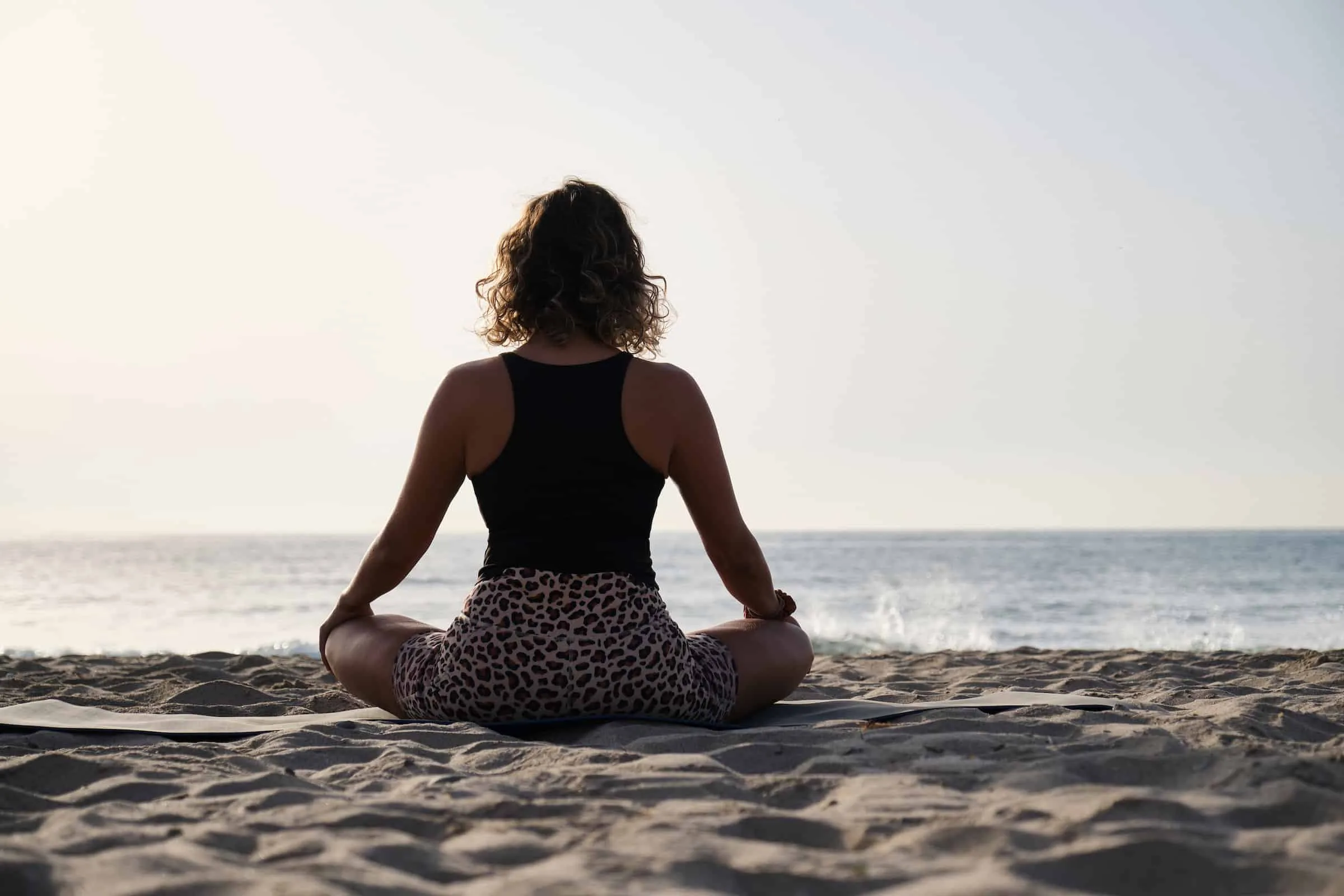A woman practicing yoga at the sunrise on the beach