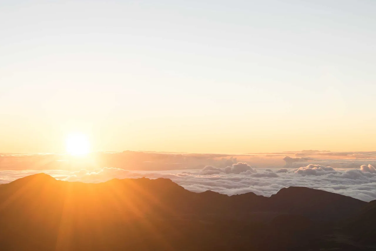 a sunset over a mountain range and clouds
